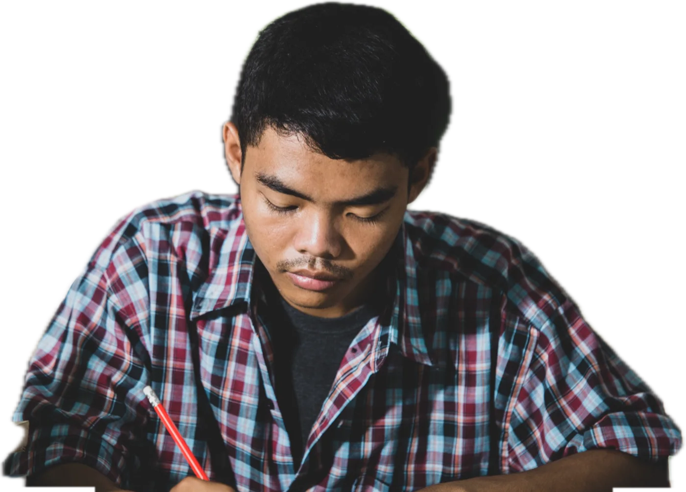 A student in a checked shirt writing in his notebook.